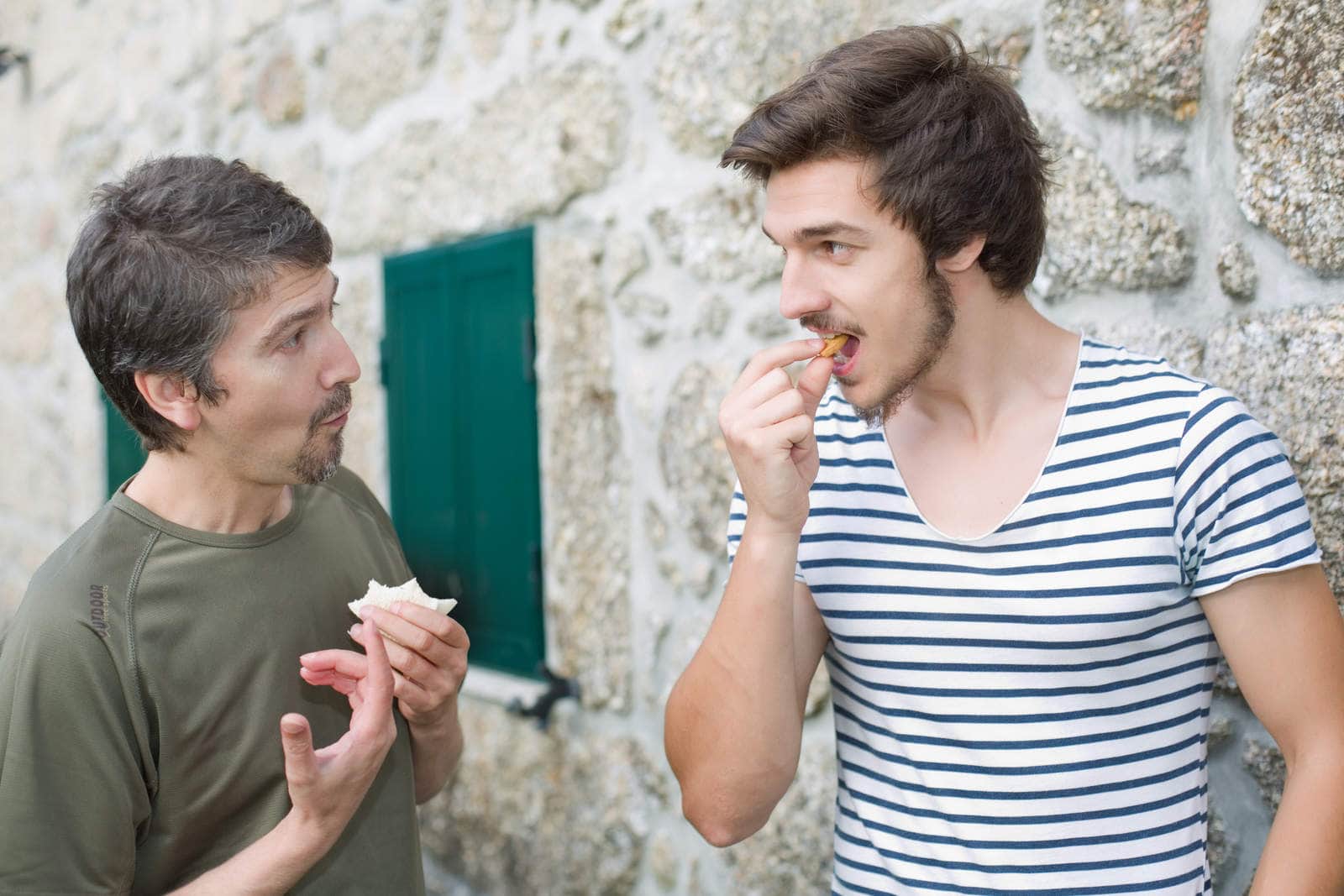 two men communicating and eating pizza